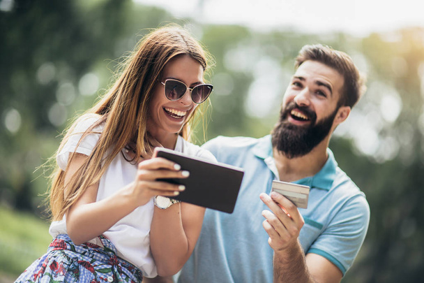 glückliches Paar bezahlt online mit Kreditkarte und digitalem Tablet  - Foto, Bild