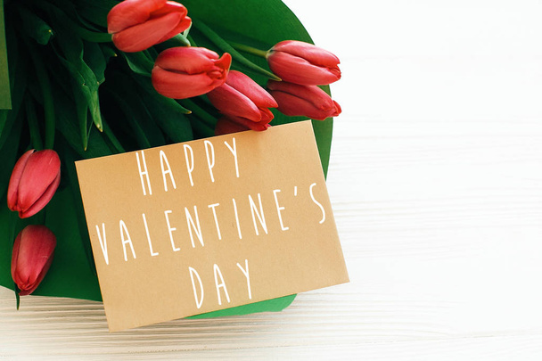 Happy Valentine's Day tekst en mooie rode tulpen op witte WoO - Foto, afbeelding
