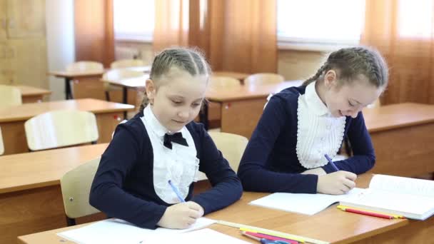 Girls schoolgirl peep each other in a notebook.Schoolgirls teenagers look at each other in a notebook during the control work in the classroom at the lesson - Footage, Video