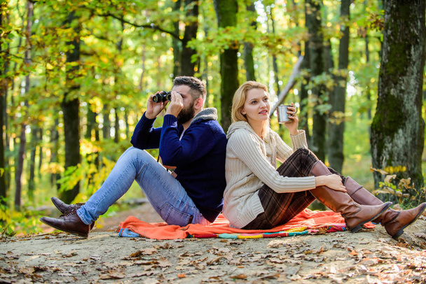 Relaxing in park together. Happy loving couple relaxing in park together. Couple in love tourists relaxing picnic blanket. Man with binoculars and woman with metal mug enjoy nature park. Park date - Φωτογραφία, εικόνα