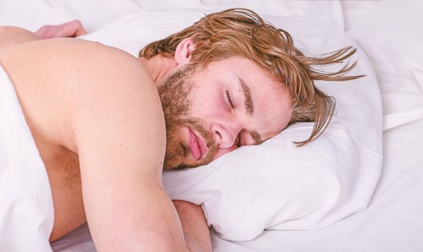 How much sleep you actually need. Man handsome guy lay in bed. Get adequate and consistent amount of sleep every night. Expert tips on sleeping better. Bearded man sleeping face relaxing on pillow - Photo, image