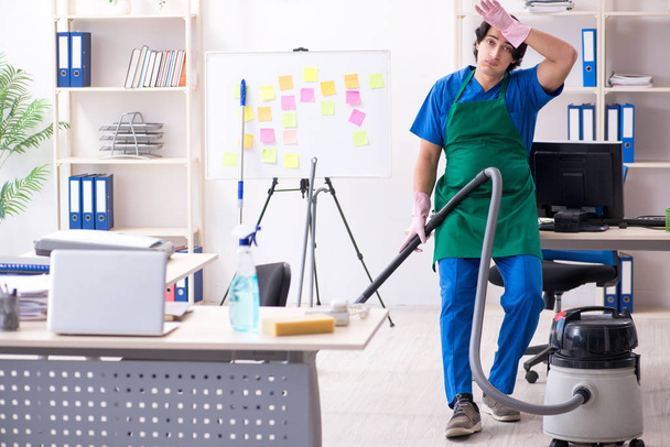Мужчина красивый профессиональный уборщик работает в офисе  - Фото, изображение