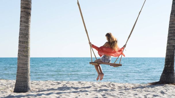 Vacation concept. Young woman swing on a beach swing. Happy traveller women on the Phu Quoc beach - Foto, Imagem