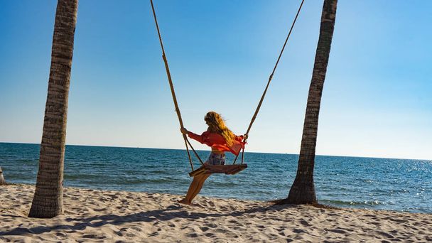 Vacation concept. Young woman swing on a beach swing. Happy traveller women on the Phu Quoc beach - Fotoğraf, Görsel