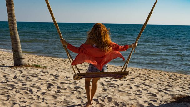 Vacation concept. Young woman swing on a beach swing. Happy traveller women on the Phu Quoc beach - Foto, afbeelding