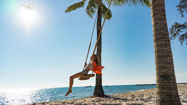 Vacation concept. Young woman swing on a beach swing. Happy traveller women on the Phu Quoc beach - Foto, Imagem