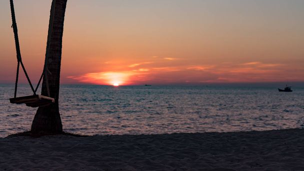 Гойдалка на красивому пляжі з красивим помаранчевим заходом сонця з білим піском і кришталево чистим блакитним водяним фоном для концепції туризму
 - Фото, зображення