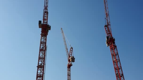 Три строительных крана, которые стоят бок о бок против голубого безоблачного неба. Вид с прогулочной лодки
 - Кадры, видео