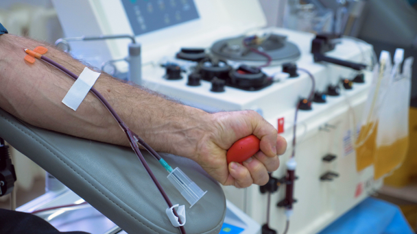 Mannelijke hand is knijpen een bal terwijl het geven van bloed - Video