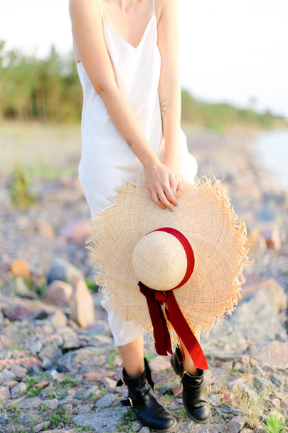Femme caucasienne debout sur la plage de bardeaux avec chapeau dans les mains
. - Photo, image