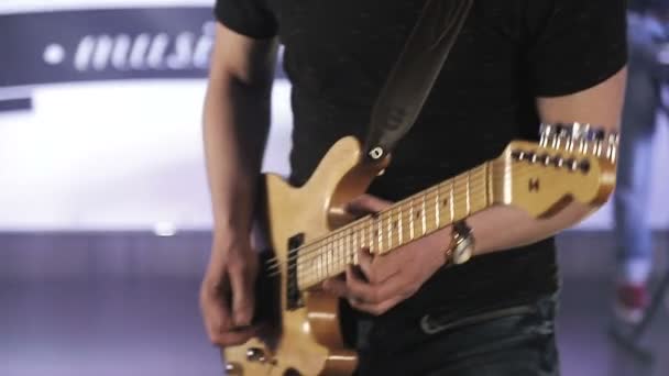 Rock musician plays yellow electric guitar, on stage with colored light - Footage, Video