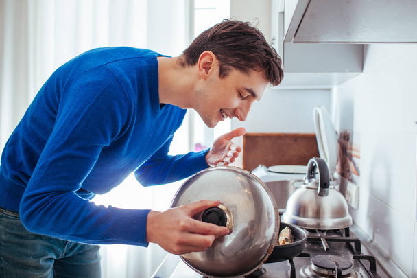 jeune homme reniflant la nourriture de la casserole
 - Photo, image