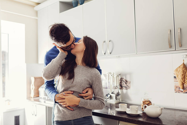 Молода пара на кухні обіймає і цілує
 - Фото, зображення