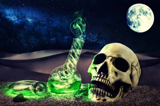 Composizione di Halloween in scena desertica con teschio e misteriose bottiglie fumanti. Luna piena sullo sfondo
. - Foto, immagini