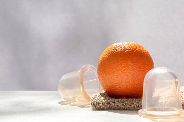 L'orange se trouve sur un gant de toilette en maille fabriqué à partir de fibres naturelles, et à côté il y a des banques de vide
. - Photo, image