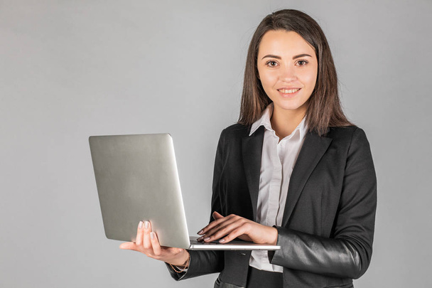 Photo of a young cheerful business woman standing over a gray wa - Photo, Image