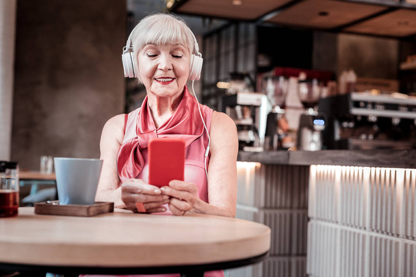 Peaceful short-haired old woman enjoying favorite music - Foto, afbeelding