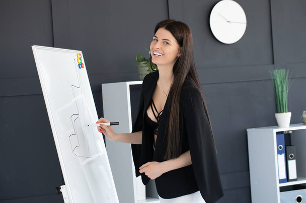 Young woman planning writing day plan on white board, holding marker in right hand.  - Photo, Image