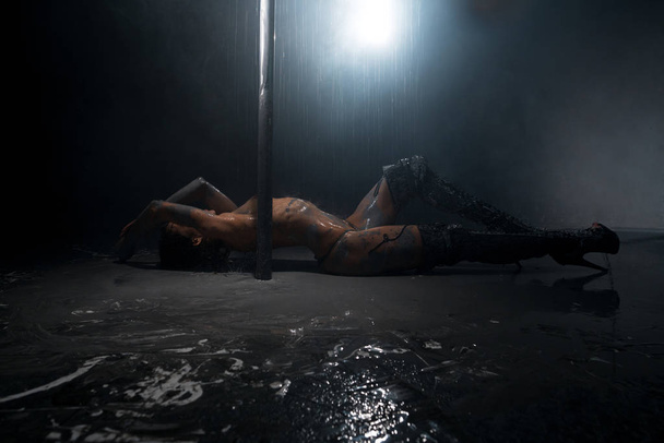 Brunette topless lying on floor in mud and rain - Foto, imagen