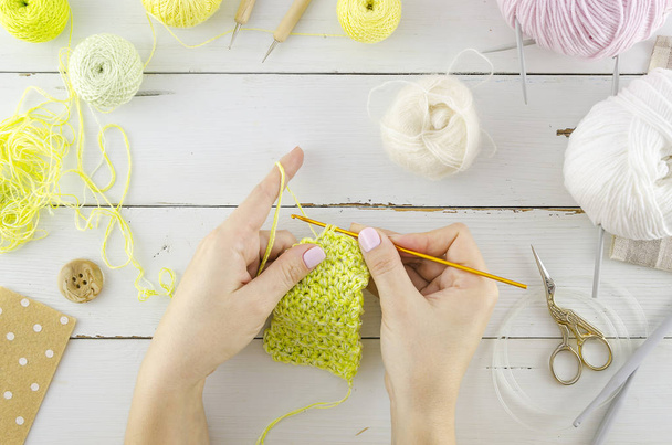 女は服を編むツールや編み物の付属品と白い机を表示します。女性の手は編み針を保持 - 写真・画像