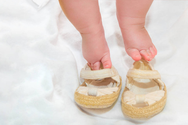 Shoes for a newborn baby, baby booties on the background of small legs. - Fotó, kép