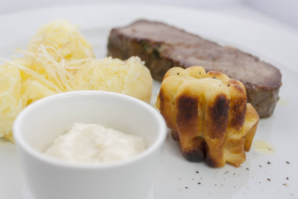 budín de yorkshire y rosbif con puré de papas y salsa de crema agria en un plato blanco
 - Foto, imagen