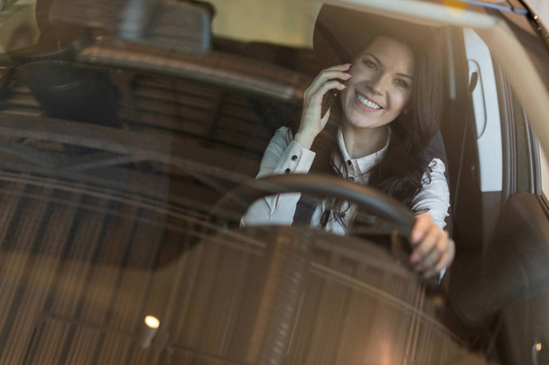 Gelukkige vrouw koper zittend in haar nieuwe voertuig in de auto dealer - Foto, afbeelding