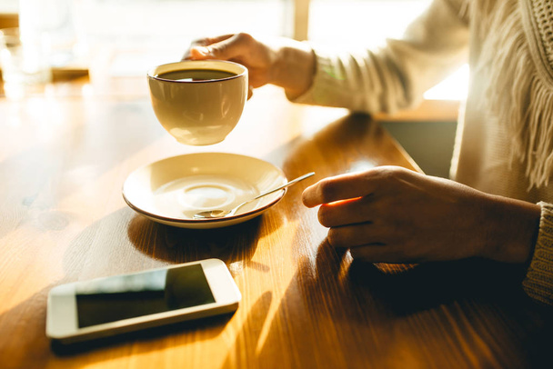 Žena drží v ruce šálek kávy na dřevěném pozadí - Fotografie, Obrázek