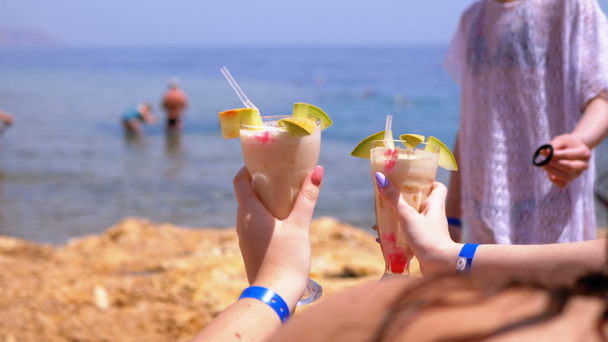 Два екзотичних коктейлі в руках дівчат на фоні моря і пляжу в Єгипті. - Кадри, відео