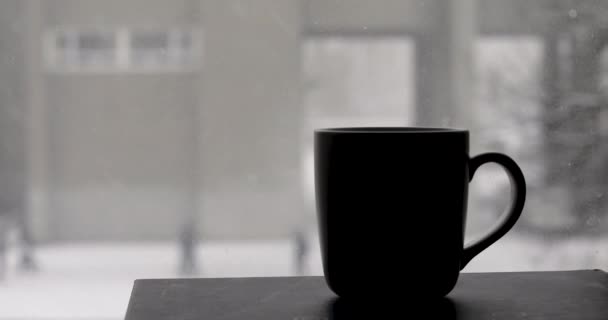 Cup with a hot drink and snow falls - Filmati, video