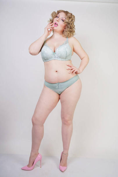 Pretty caucasian chubby woman with plus size body and pale skin wearing green lace sexy underwear on white studio background - Photo, Image