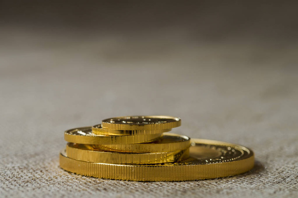 Een stapel gouden munten van verschillende grootte op een achtergrond van ruwe hout textuur. - Foto, afbeelding