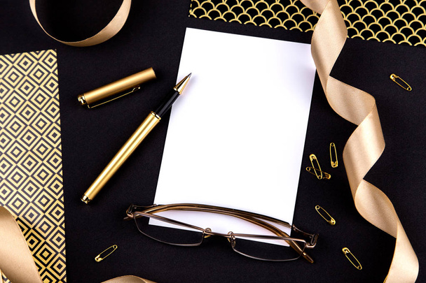 Gouden pen, lint, paperclips en briefpapier op een zwarte backgrou - Foto, afbeelding