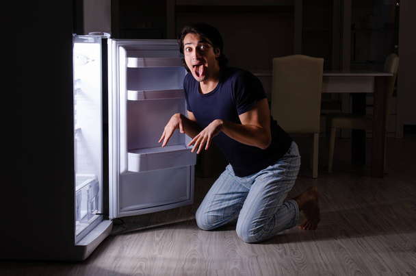Homem quebrando dieta à noite perto da geladeira - Foto, Imagem