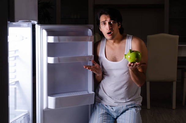 Man breekt dieet 's nachts in de buurt van koelkast - Foto, afbeelding