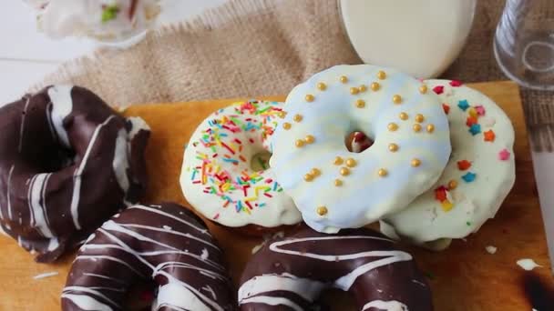 multicolored donuts and chocolate. Donuts with milk. Young guy takes a donut - Footage, Video