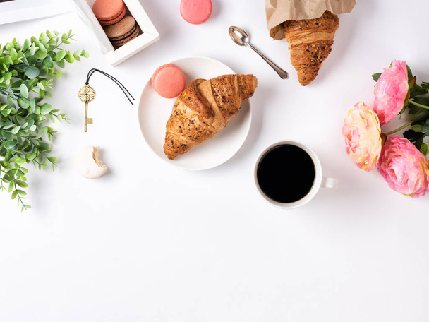 White table's surface with coffee, croissant, macarons, and flowers - Photo, Image