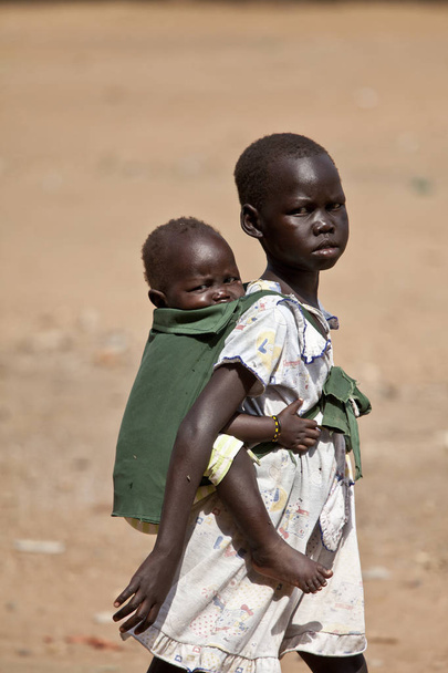 Girl carrying her sister in South Sudan - Фото, изображение