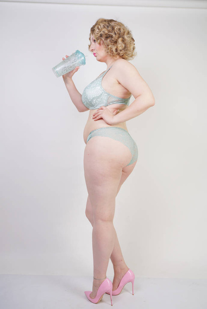 Mooie Kaukasische Mollige vrouw met plus grootte lichaam en bleke huid dragen groene kant sexy ondergoed op witte studio achtergrond - Foto, afbeelding