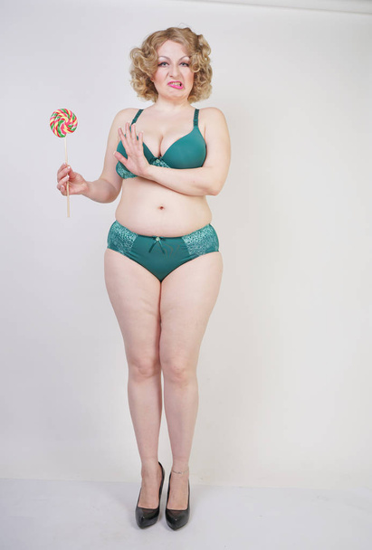 adult overweight woman stands in lingerie and hates her belly and fat on white background in Studio - Photo, Image