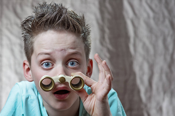 surprised teen boy emotionally looking through binoculars - Фото, изображение