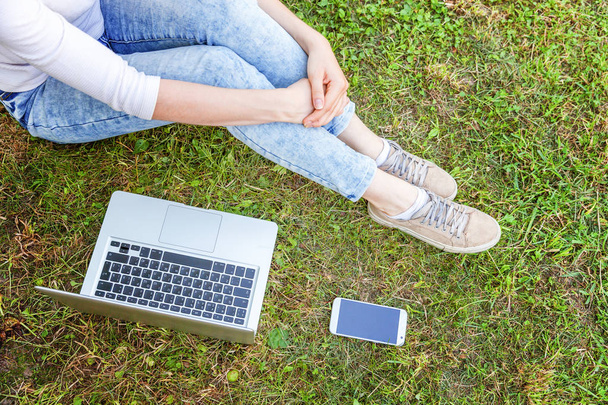 Nő lába, zöld a fű a gyep a városi park, kezében laptop pc számítógépen dolgozik. Szabadúszó üzleti koncepció - Fotó, kép