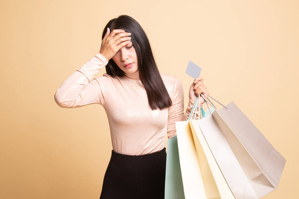 Unhappy  young Asian woman with shopping bags and credit card. - 写真・画像
