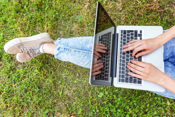 Kobieta nogi na Zielona trawa trawnik w parku miejskim, rąk do pracy na komputerze pc laptop. Koncepcja działalności freelancerskiej - Zdjęcie, obraz