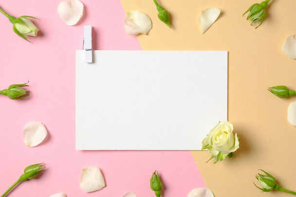 Blank white paper with clothespin and flowers on pink and yellow background. Top view, tender minimal flat lay style composition. Women desk, fashion blogger, love, tenderness concept. - Fotó, kép