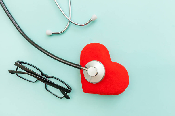Medicine berendezések sztetoszkóp vagy fonendoszkóp szemüveg és piros szív izolált trendi pasztell kék háttér. A készülék az orvos. Egészségügyi életbiztosítási koncepció - Fotó, kép
