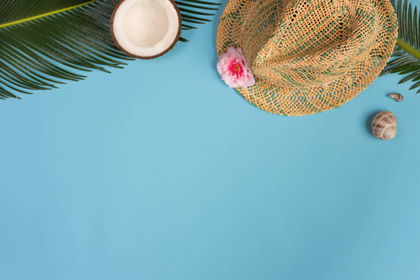 Stylish summer composition with coconut, green leaves, hat on a blue pastel background. Artwork mockup with copy space - 写真・画像