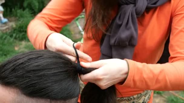 Жінка-перукар коси молодий чоловік довге волосся в косі. На відкритому повітрі. Крупним планом
. - Кадри, відео