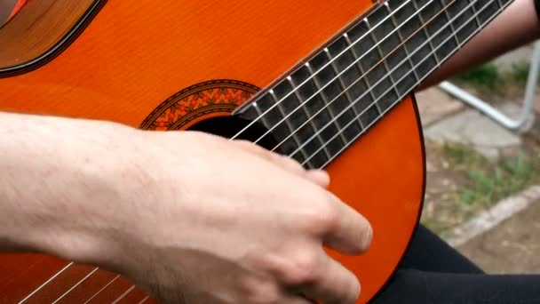 Performance musician. Guitarist plays with his fingers on an acoustic wooden guitar. Outdoors. Close-up. - Footage, Video