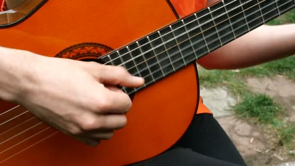 Performance zenész. A gitáros az ujjaival játszik akusztikus, fából készült gitáron. Szabadban. Közeli. - Felvétel, videó